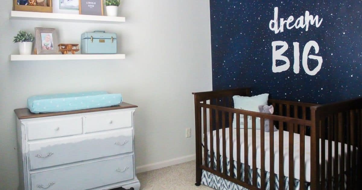 12 Beautiful Boy Nursery Ideas Navy and gray nursery with a dark wood crib, white dresser, floating shelves, and a starry accent wall featuring the words "Dream Big."