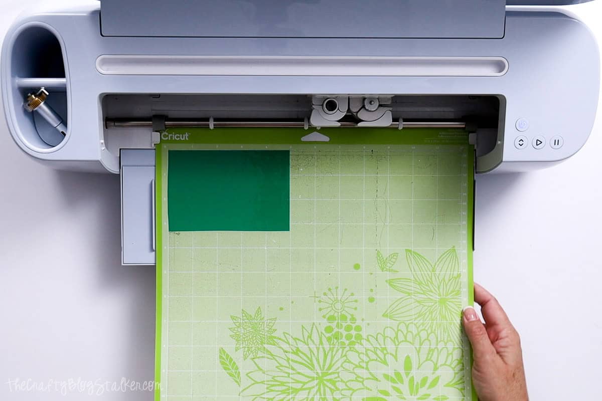 Loading green vinyl on a StandardGrip mat into cricut cutting machine.