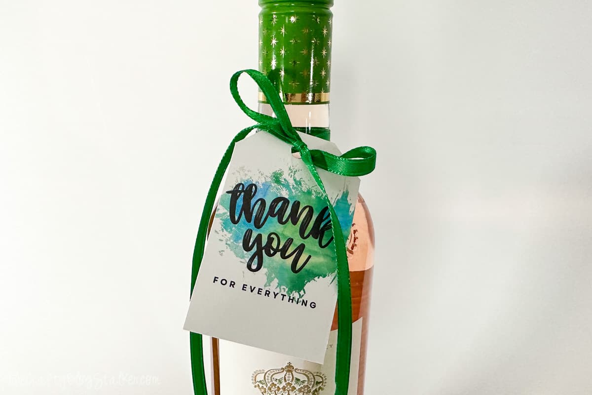 Thank you tag tied to a bottle of wine with green ribbon.