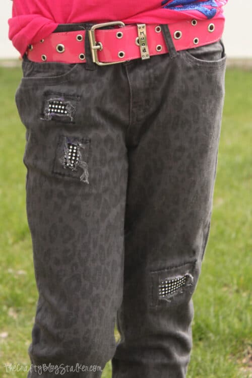 A girl wearing jeans that have bling patches sewn in.