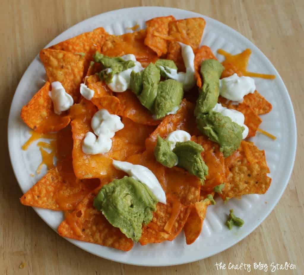 image of a place of quick and easy nachos with Doritos, melted shredded cheese, sour cream and wholly guacamole