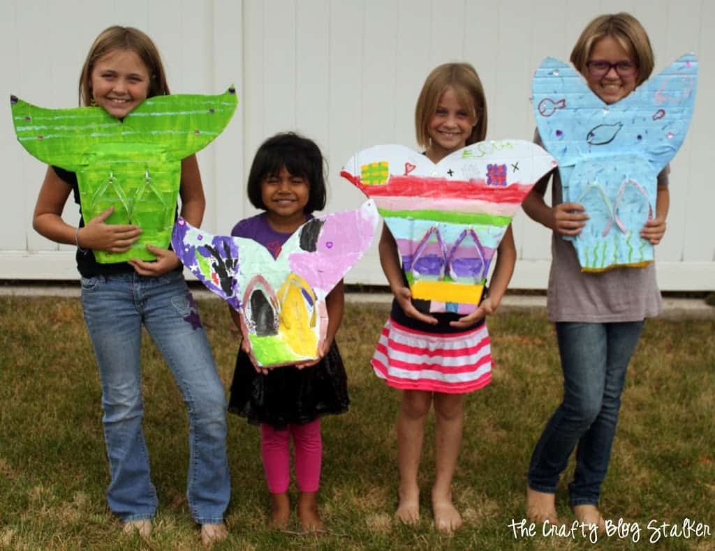 4 little girls showing off their mermaid tails they made.