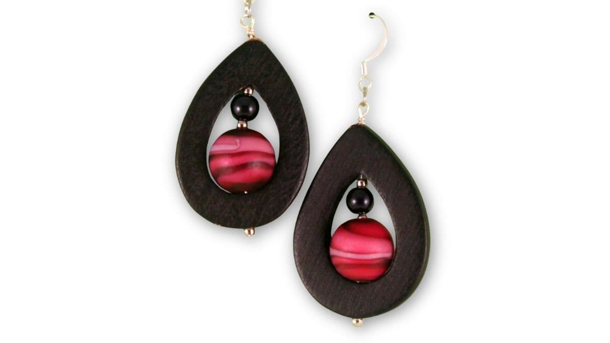 Pair of handmade teardrop earrings with black wooden frames and pink striped beads, finished with silver fishhook ear wires.