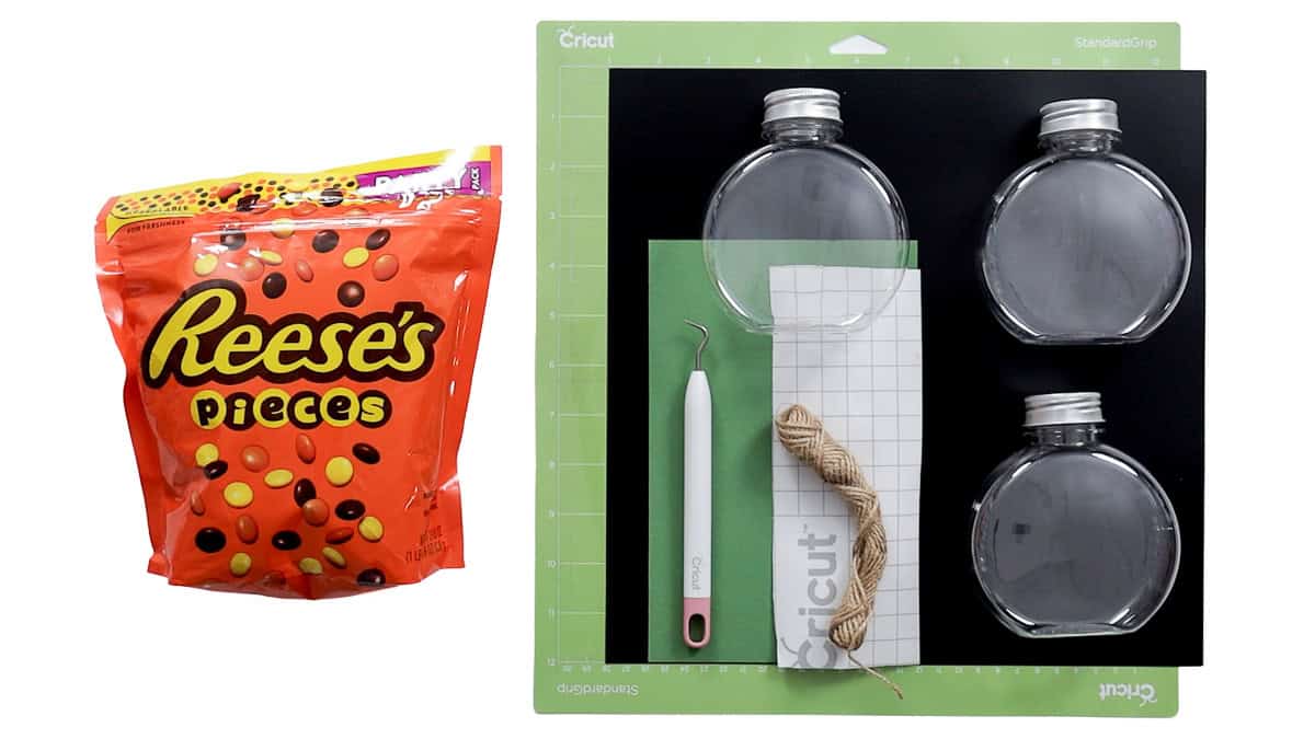 Supplies for jack-o'-lantern candy gifts including clear pumpkin jars, Reese's Pieces, Cricut vinyl, transfer tape, twine, and weeding tool.