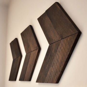 Three dark wood chevron arrows mounted on a light-colored wall, creating a bold and rustic wall art display with a modern farmhouse vibe.