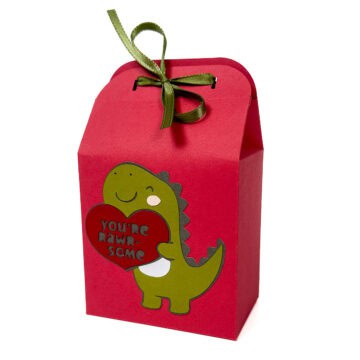 Finished dinosaur Valentine treat bag made from cardstock, featuring a layered dinosaur holding a heart and tied closed at the top with a ribbon.