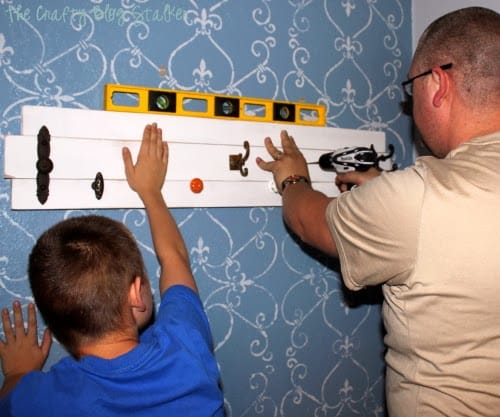 Father and son hanging a Coat Rack using a level.