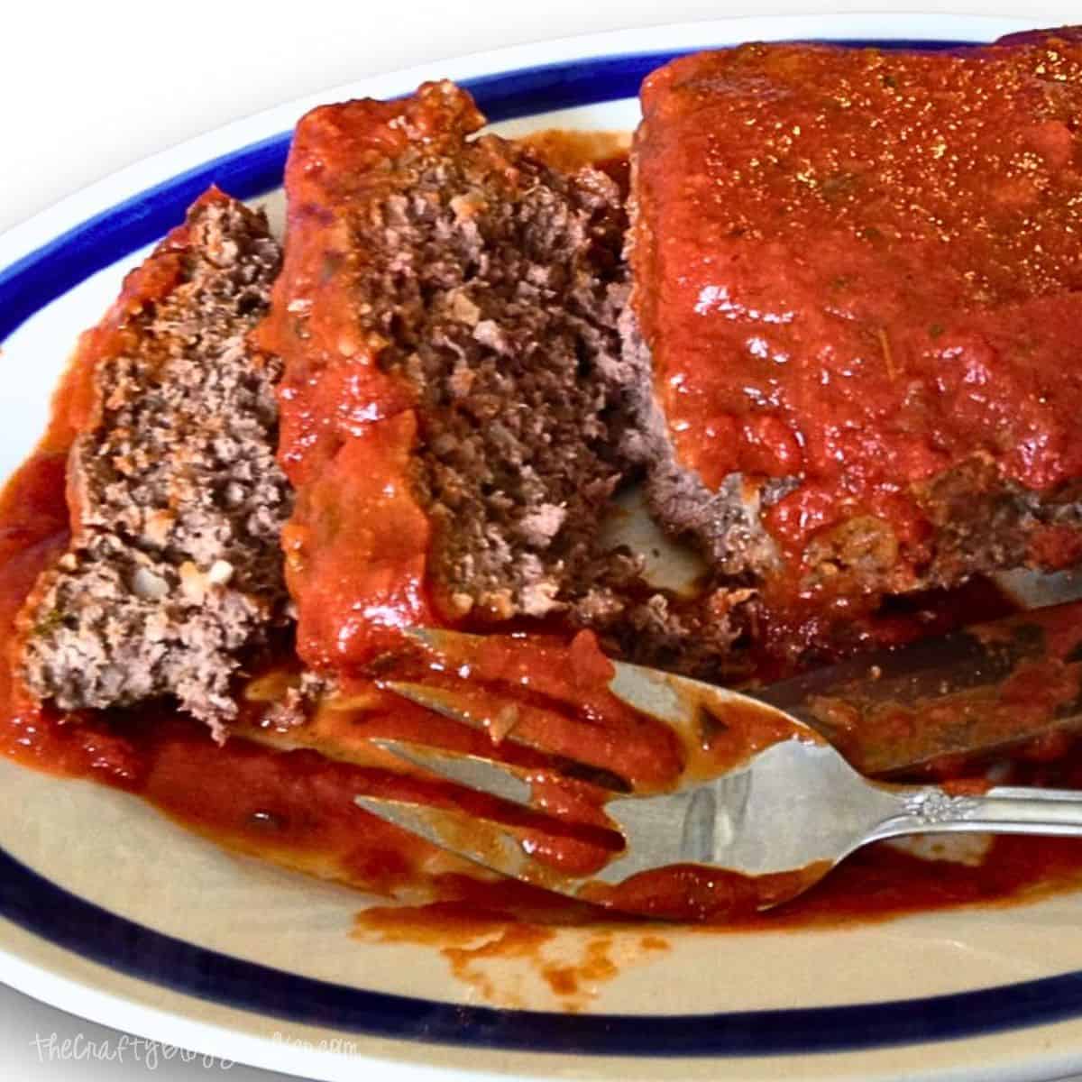 Sliced meatloaf on a white plate with a fork and knife.