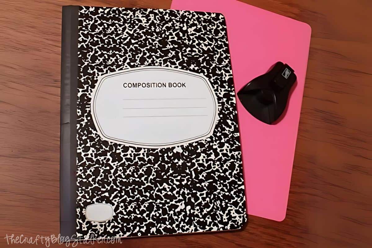 A composition notebook with a piece of cardstock cut to the same size, and the corners have been rounded with a paper punch.