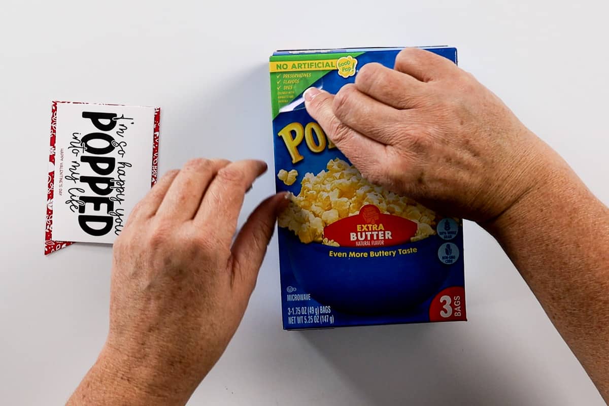 Applying a glue dot to the front of a popcorn box.