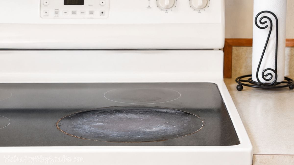 Dirty glass top stove with burned-on residue and cloudy buildup on the front burner of a white electric range.