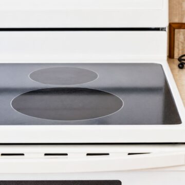 Clean black glass top stove with polished burners and a spotless surface on a white electric range after cleaning.
