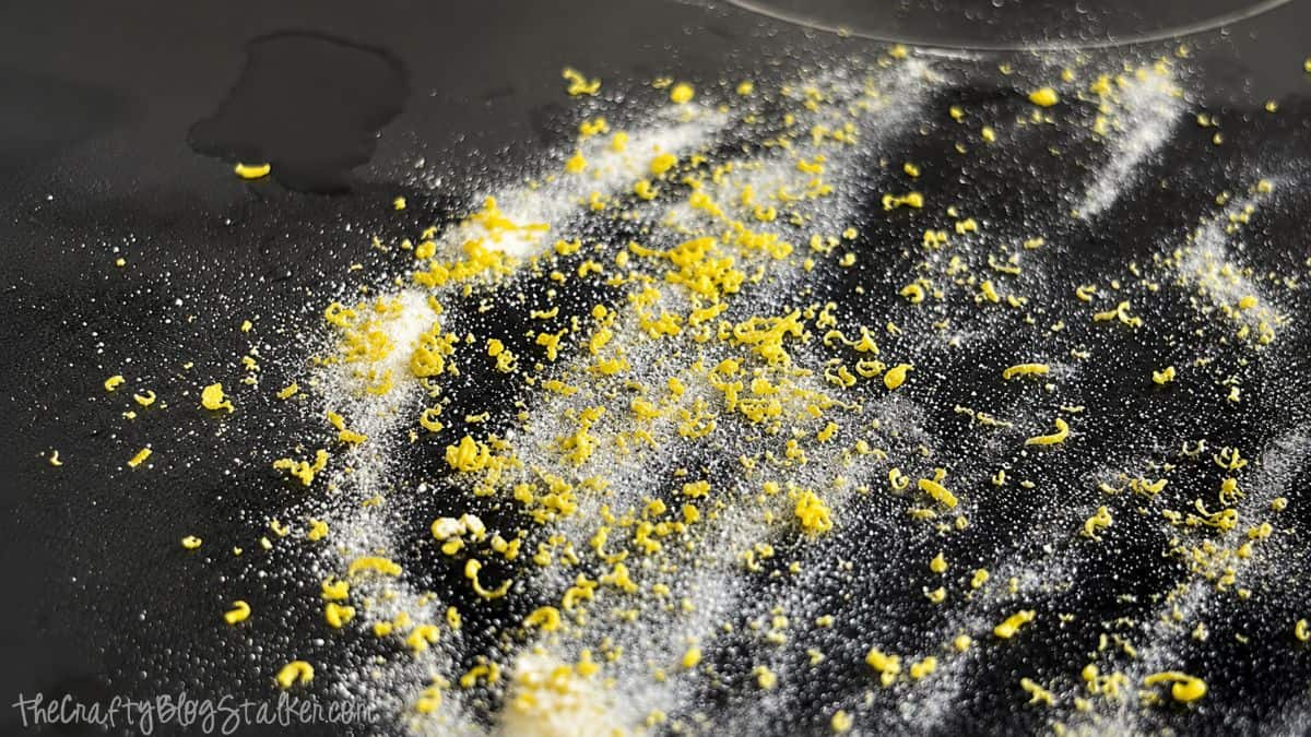 Baking soda and lemon zest sprinkled across a glass top stove surface during a homemade stove cleaning process.