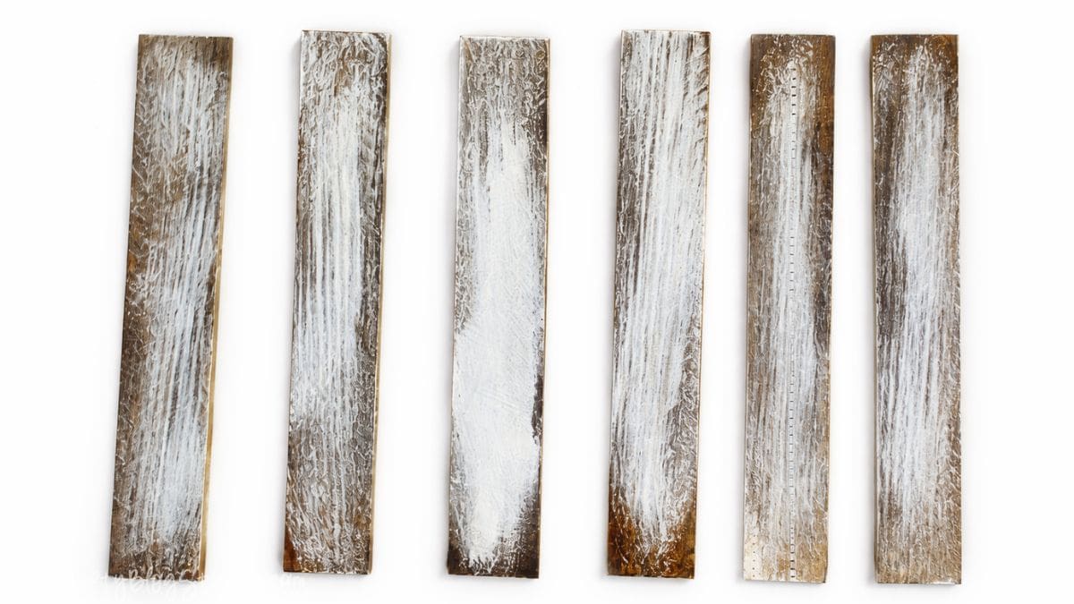 Make new wood look OLD with this tutorial on how to Weather Wood. Click through for instructions Six narrow wood planks arranged in a row, each showing a dry brushed finish that creates a weathered, rustic wood texture.
