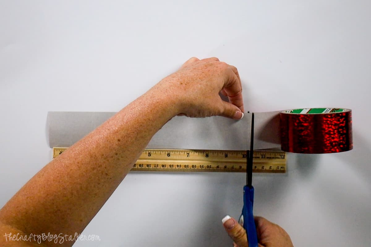 Hands cutting duct tape with a pair of scissors.