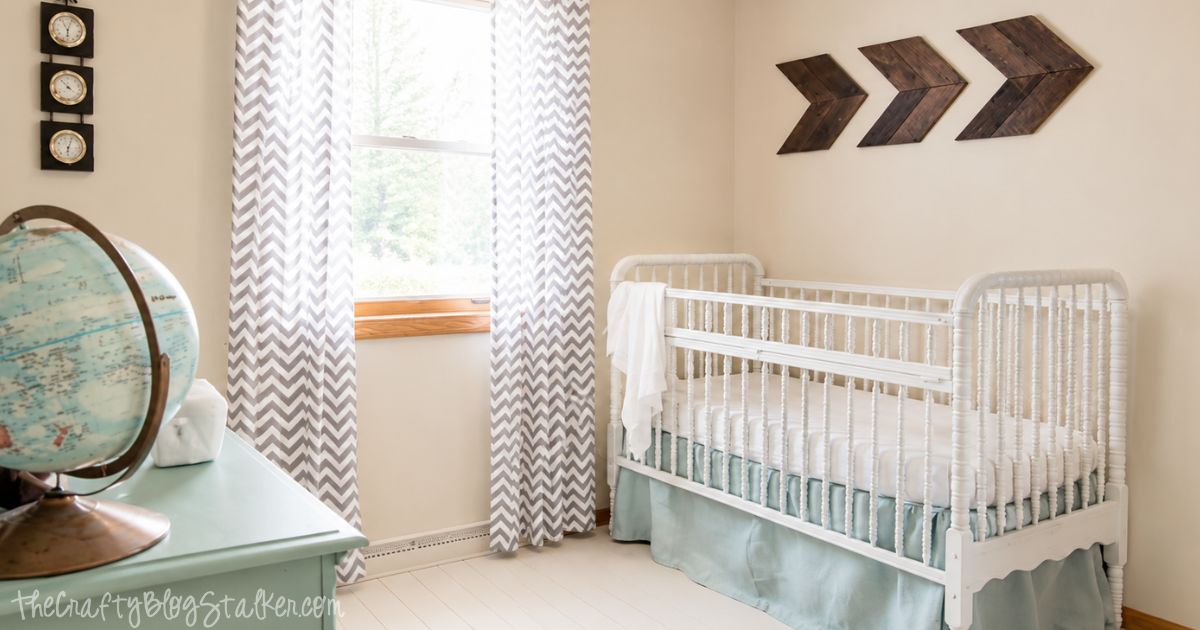 A precious Vintage Travel Themed Nursery. Such a beautiful room! Travel-themed nursery with a white crib, globe on a mint dresser, gray chevron curtains, wood arrow wall decor, and light blue bedding.