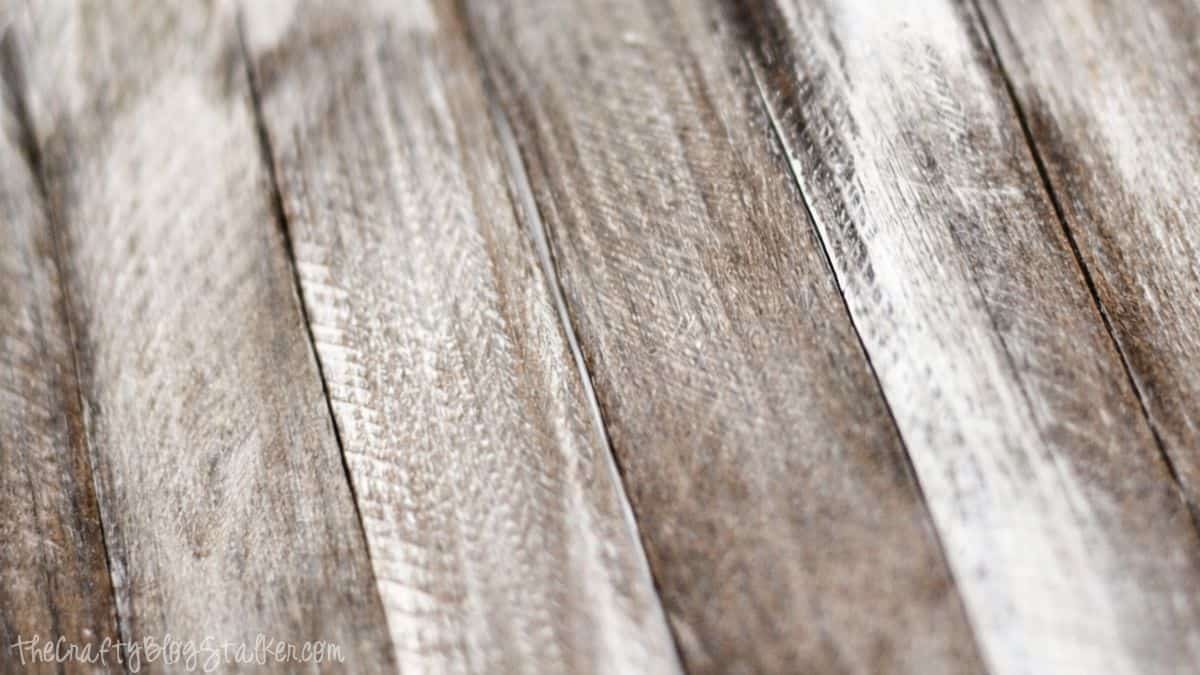 Close-up of weathered wooden planks with a rustic, distressed texture, often used as a neutral background for crafts or photography.