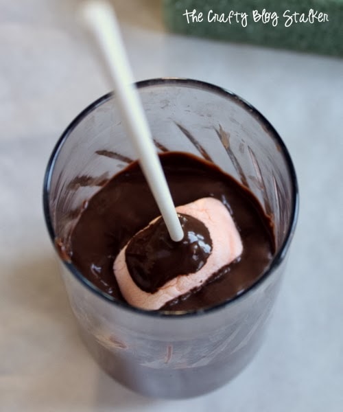 dipping the marshmallow into melted chocolate