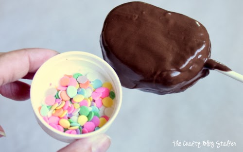 adding sprinkles to chocolate marshmallow pops