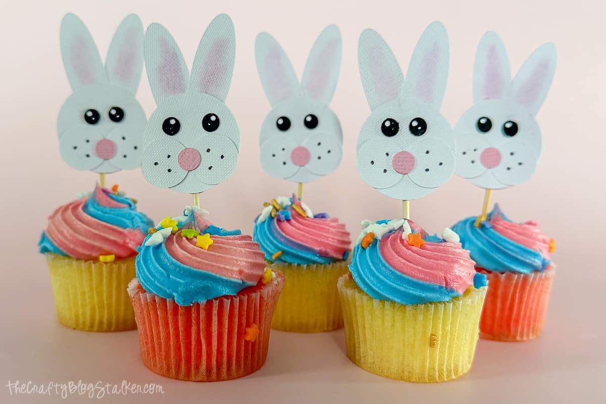 Five mini cupcakes with bunny cupcake toppers.