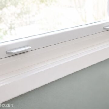 Close-up of a white painted window trim and sill above a light green wall, showing clean molding details and a freshly finished surface.