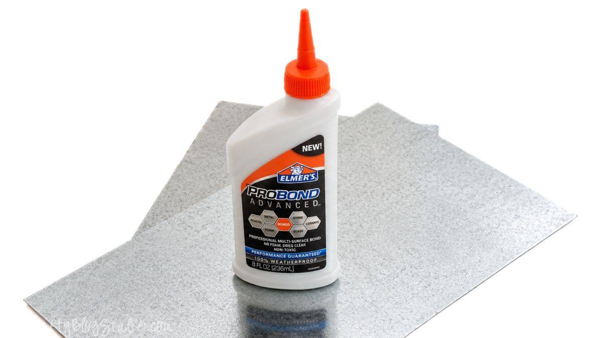 Bottle of Elmer's ProBond adhesive placed on galvanized sheet metal, showing the materials used for a magnetic medicine cabinet project.