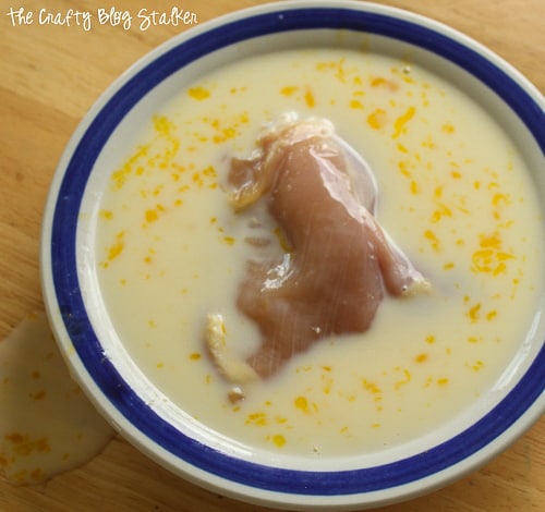 dipping chicken thighs into a bowl with milk and egg