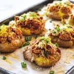 BBQ chicken smashed potatoes topped with shredded cheese and green onions, baked on a sheet pan until crispy and golden brown.