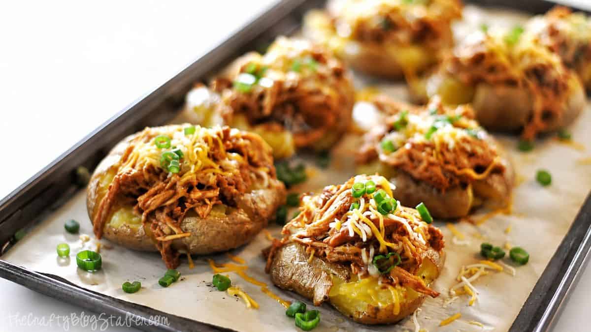 BBQ chicken smashed potatoes topped with shredded cheese and green onions, baked on a sheet pan until crispy and golden brown.