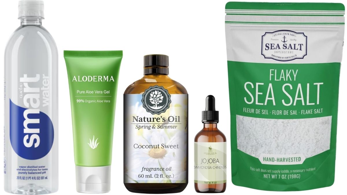 Bottle of water, aloe vera gel, fragrance oil, jojoba oil, and a bag of flaky sea salt arranged as ingredients for beach spray.