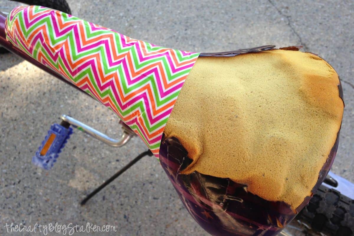Torn bike seat with three strips of duck tape.