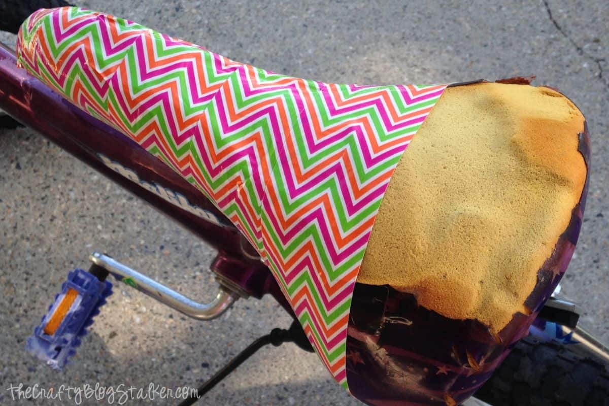 Torn bike seat with four strips of duck tape.