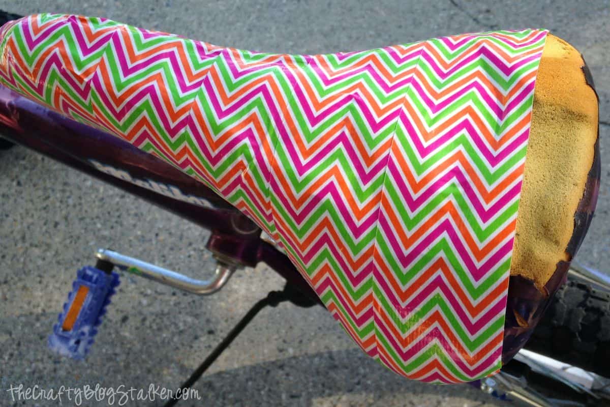 Torn bike seat with five strips of duck tape.