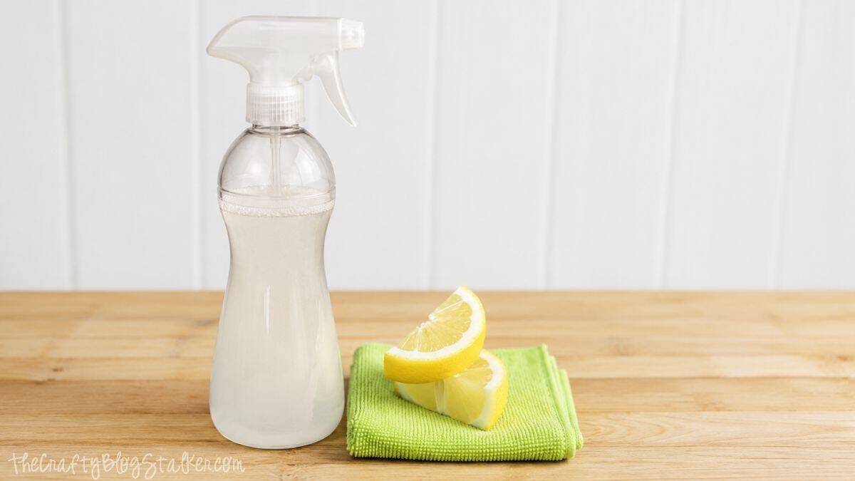 Looking for a safe alternative to cleaners? Try this Vinegar All Purpose Cleaner! Spray bottle of homemade all-purpose cleaner beside lemon wedges and a green microfiber cloth on a wooden countertop.