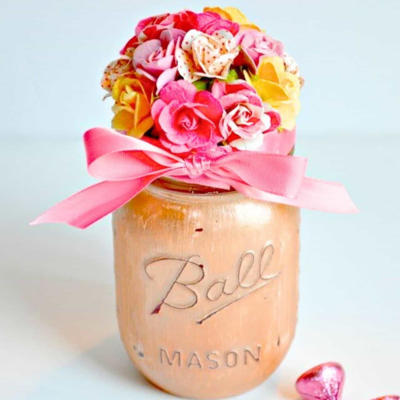 Painted Ball mason jar filled with colorful faux flowers and tied with a pink ribbon for a handmade floral gift or decor idea.