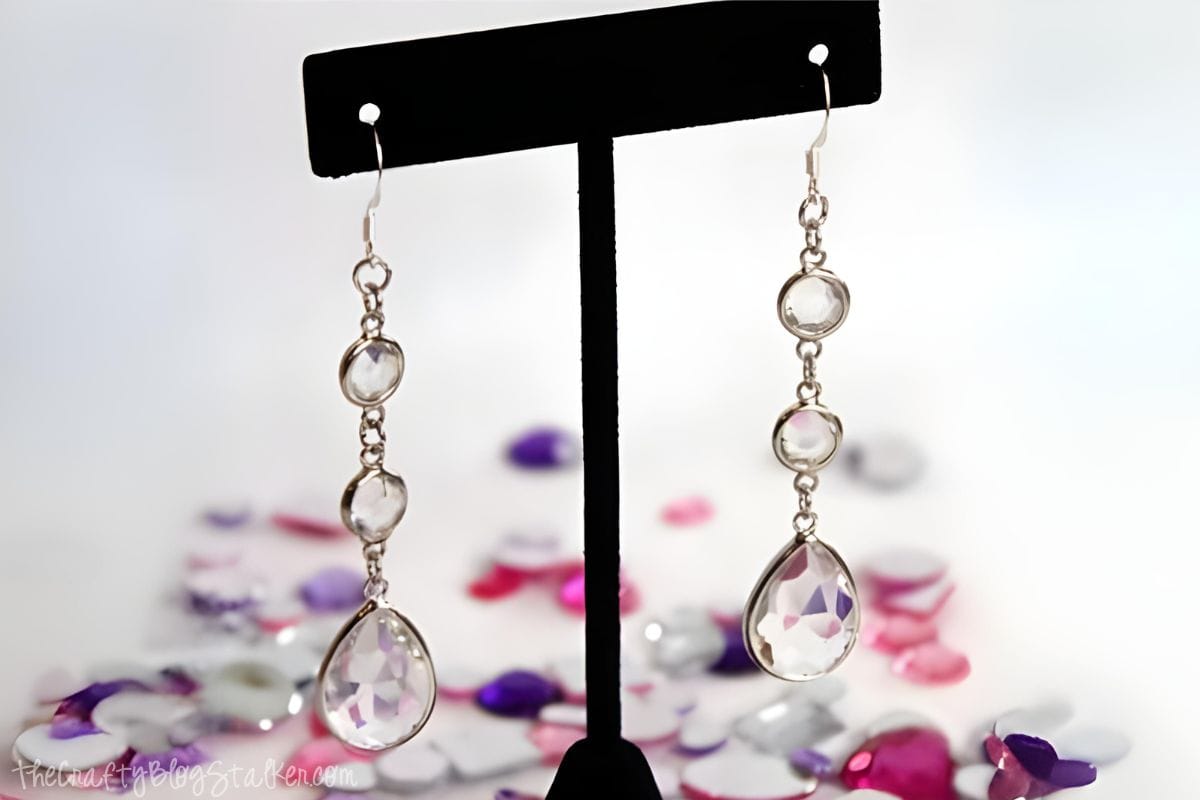 Rhinestone drop earrings displayed on an earring stand.