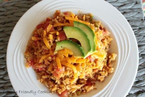 an image of a white bowl filled with spanish rice topped with a sliced avocado