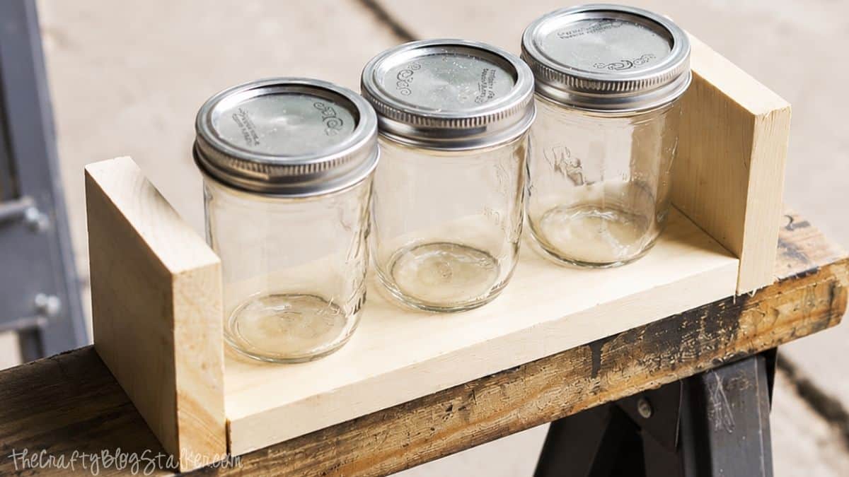 Make your very own Chalkboard Candle Box complete with DIY Citronella Candles Unfinished wooden box holding three mason jars with lids, showing the basic frame for a DIY citronella candle box project.