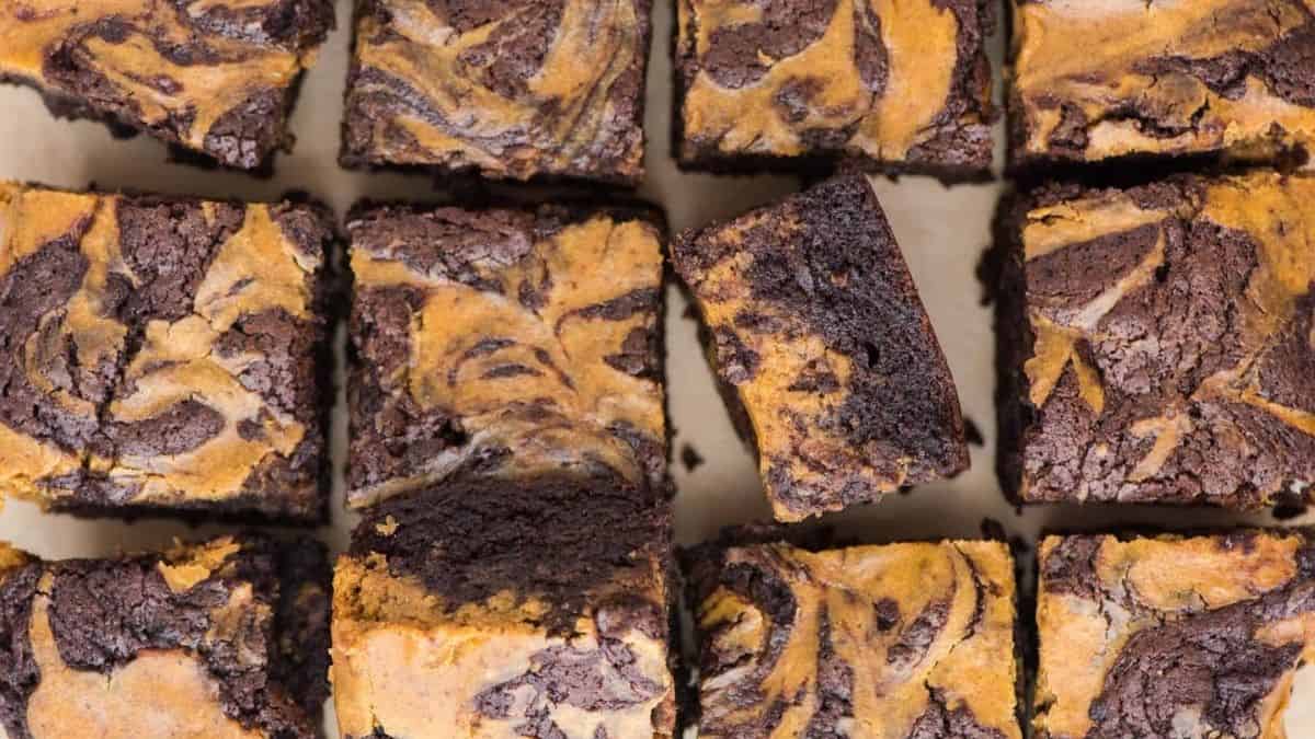 Pumpkin cheesecake brownies cut into squares, showing a rich chocolate base with creamy pumpkin swirls on top.