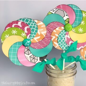 Two paper lollipops with a teal bow around the stem.