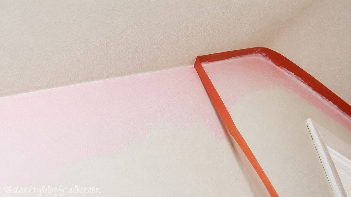 A Pink Shabby Chic Accent wall | Perfect for any little girl! Orange painter's tape lines the ceiling and wall edges as light pink paint is applied to an accent wall.