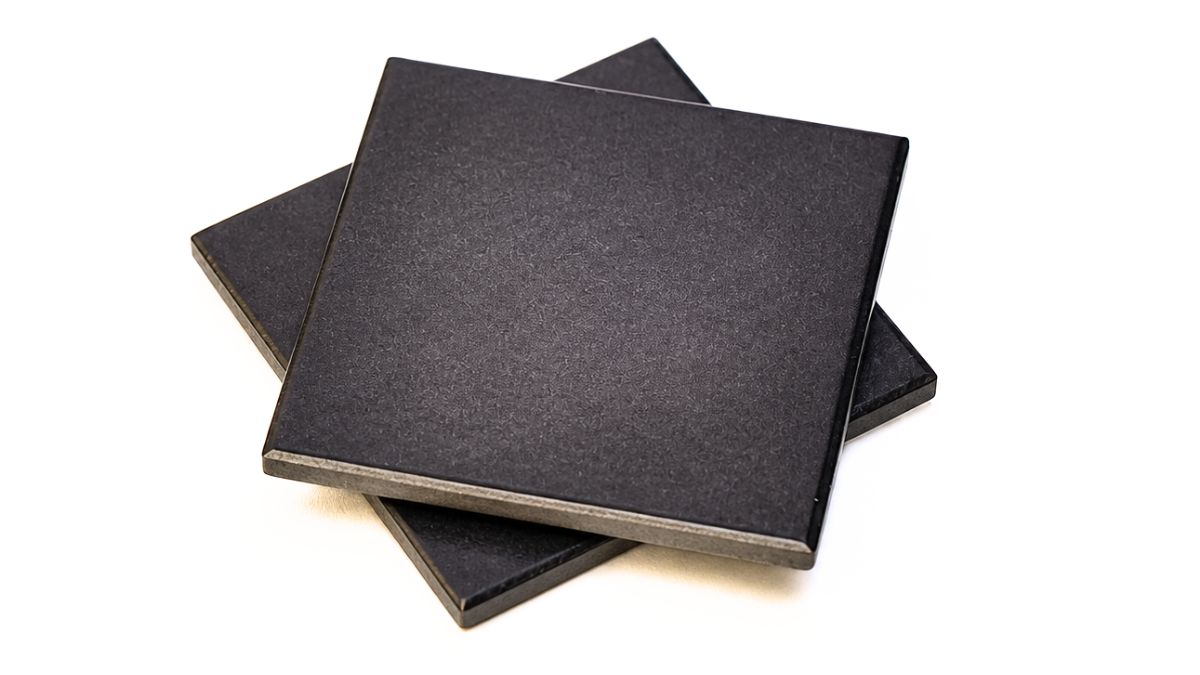 Two square coasters painted solid oil rubbed bronze, stacked slightly offset to show the edges on a white background.