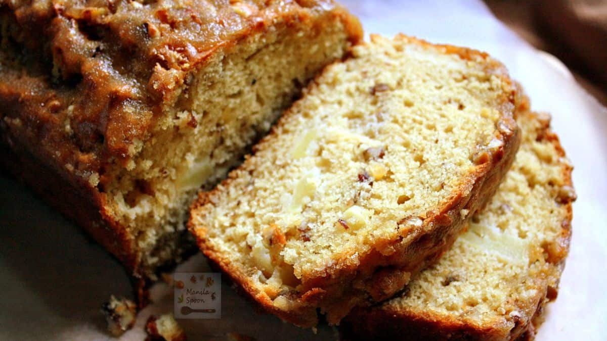 Close-up of sliced apple praline bread showing a moist texture with bits of apple and pecans, topped with a caramelized praline glaze.