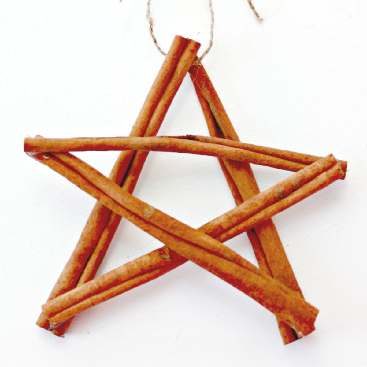 Handmade star ornament crafted from cinnamon sticks tied with twine, displayed on a white background.