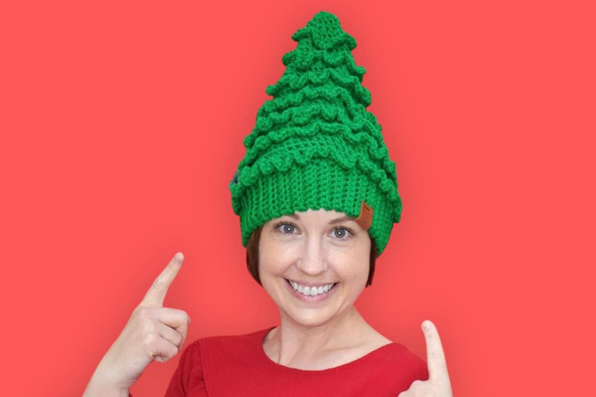 A woman wearing a Crocheted Christmas tree Hat.
