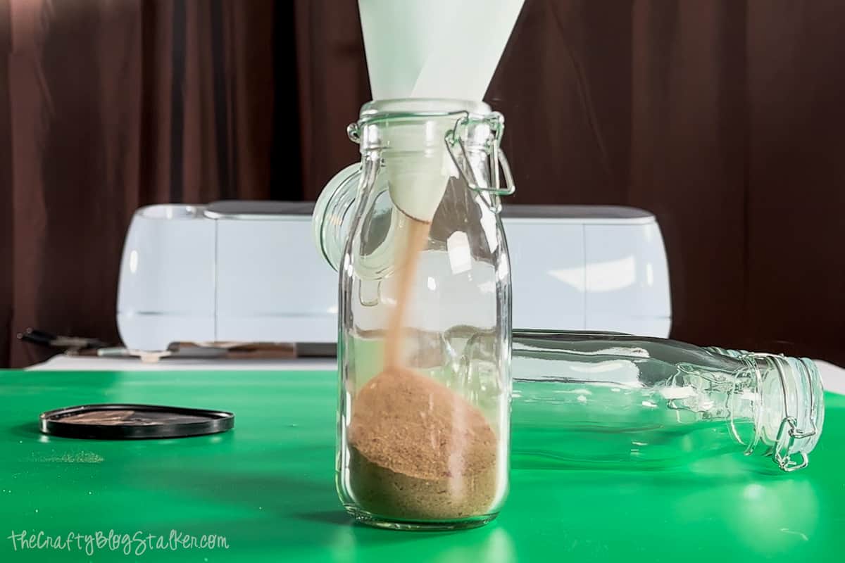 Pouring hot chocolate mix into a glass bottle with a paper funnel.