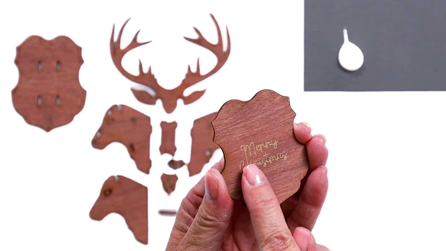 Hands holding a small wooden plaque engraved with 