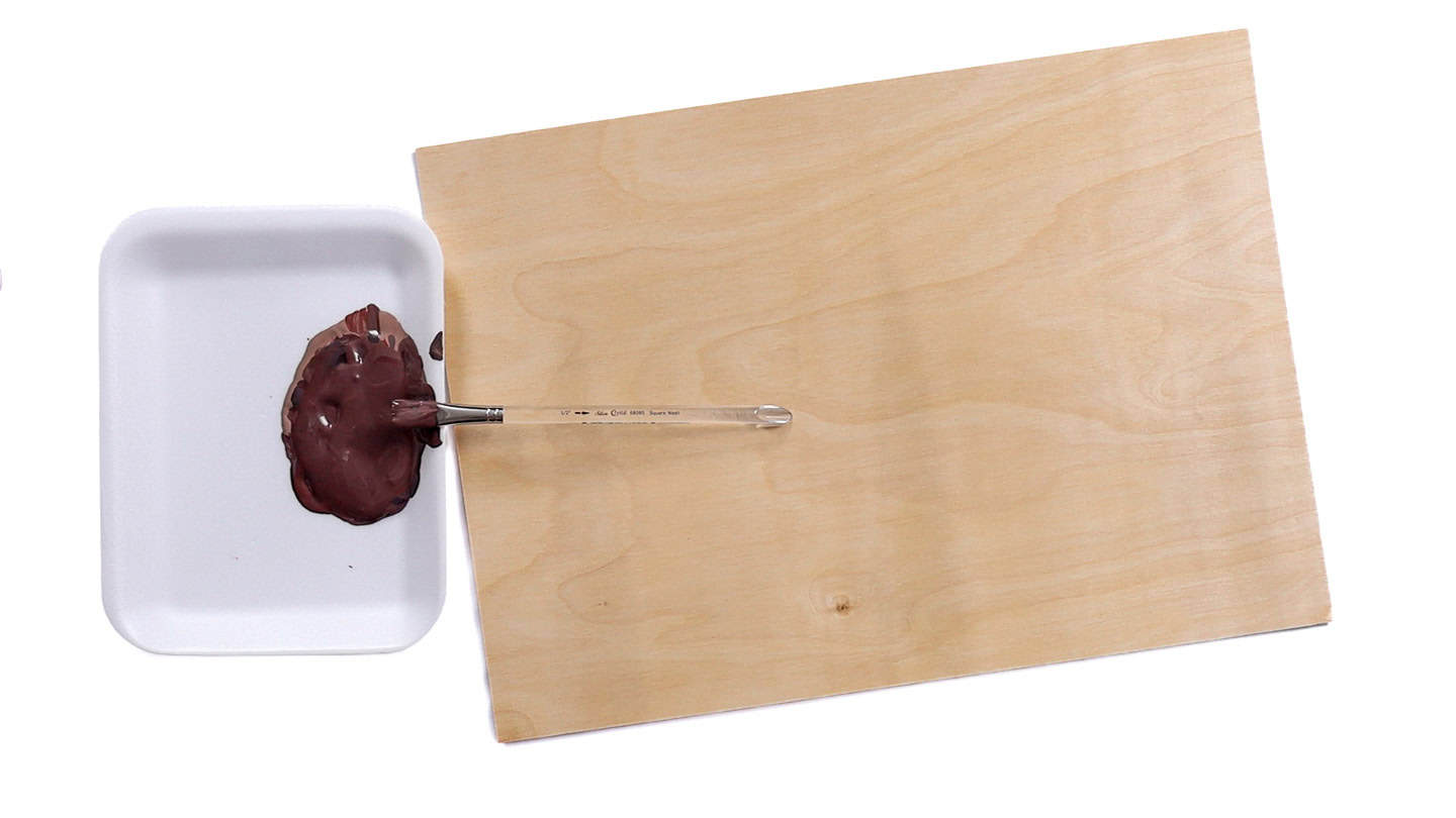 Tray with mixed brown paint and a paintbrush beside a blank sheet of wood, ready for a craft project.