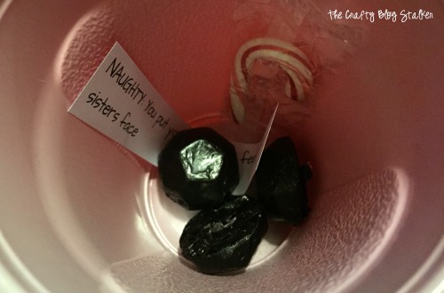 Inside a naughty cup with chocolate coal and a candy cane.