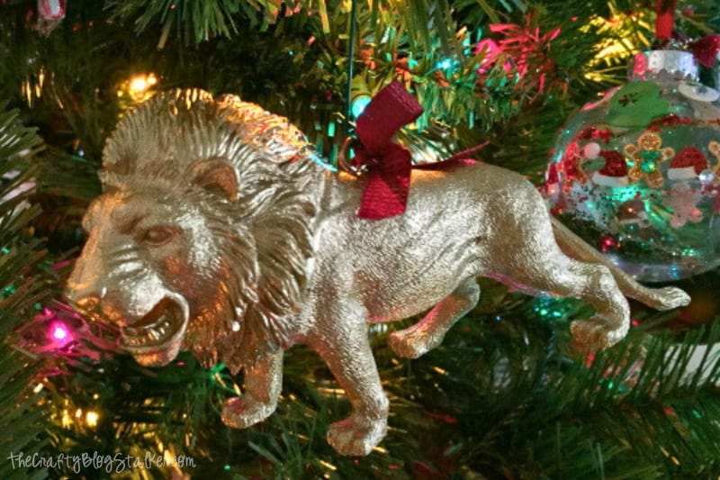 Gold painted lion ornament hanging on a Christmas tree.